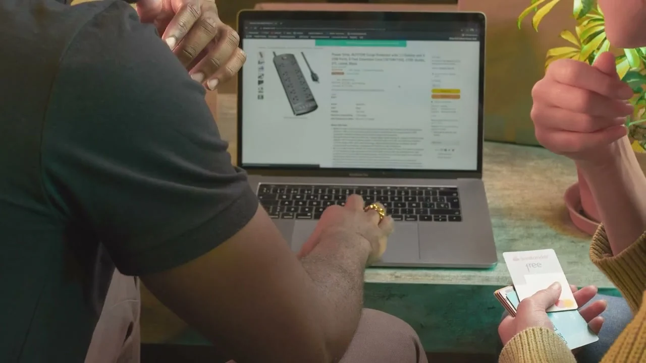 Două persoane compară produse pe un laptop.